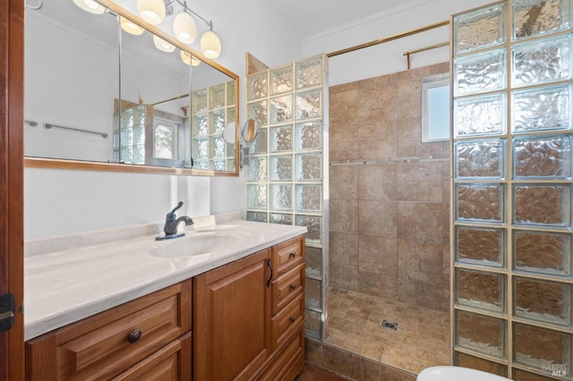 bathroom featuring tiled shower, vanity, and crown molding