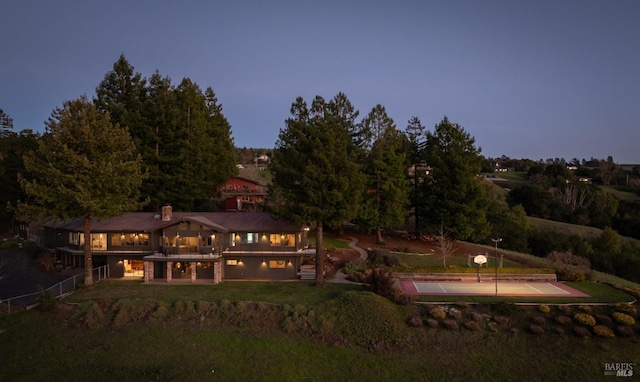 back house at dusk with a yard and a balcony