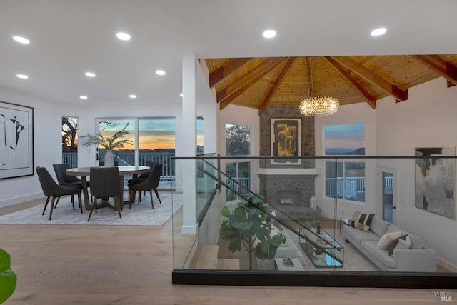 living room with wood ceiling, a fireplace, vaulted ceiling with beams, a chandelier, and light wood-type flooring