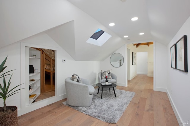 living area with light hardwood / wood-style floors, built in features, and lofted ceiling with skylight