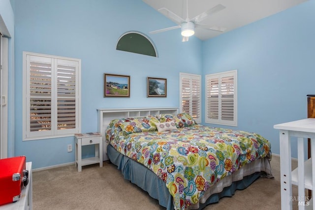 carpeted bedroom with ceiling fan and a high ceiling