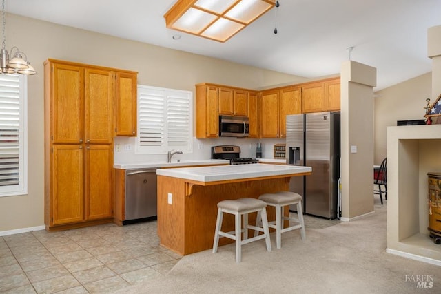 kitchen with appliances with stainless steel finishes, a kitchen island, a breakfast bar area, and hanging light fixtures