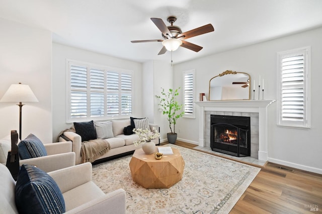 living room with ceiling fan, light wood-type flooring, and a fireplace