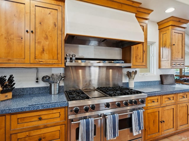 kitchen with range with two ovens, dark countertops, brown cabinetry, and custom exhaust hood