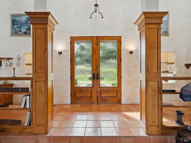 entrance foyer featuring ornate columns, a notable chandelier, and french doors