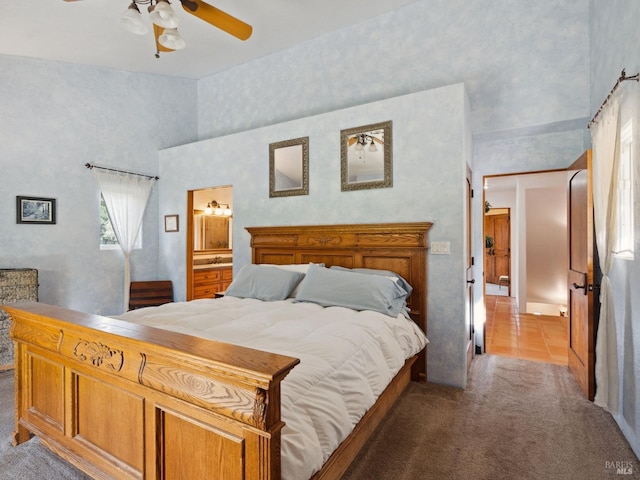 bedroom featuring light carpet, light tile patterned floors, a ceiling fan, a towering ceiling, and ensuite bath