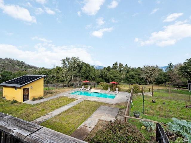 view of swimming pool with a lawn, fence, a fenced in pool, and an outdoor structure