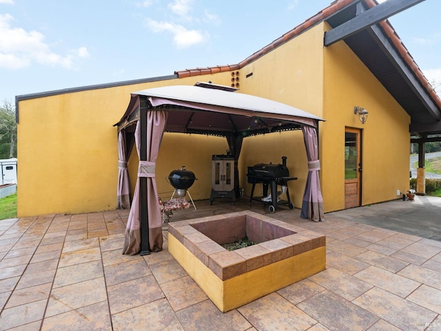 rear view of house with a patio, a fire pit, a gazebo, and stucco siding