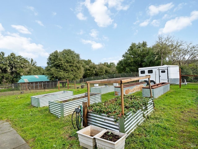 view of community with fence, a vegetable garden, and a yard