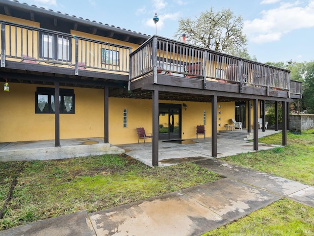 back of property with a patio area, a wooden deck, and stucco siding