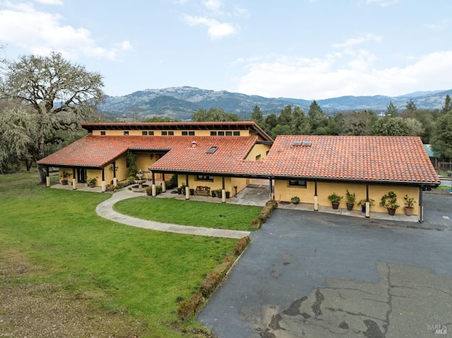 mediterranean / spanish-style house featuring a front yard, a tile roof, driveway, and a mountain view