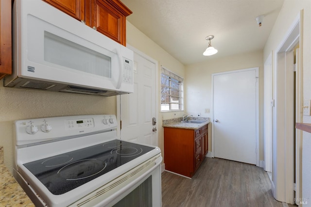 kitchen featuring dark wood-type flooring, white appliances, and sink