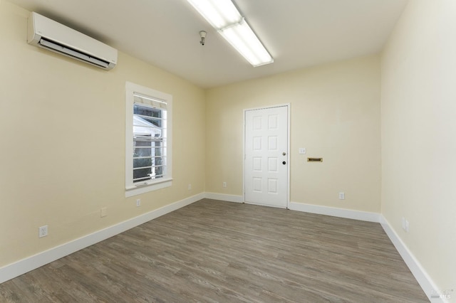 unfurnished room with wood-type flooring and a wall mounted air conditioner