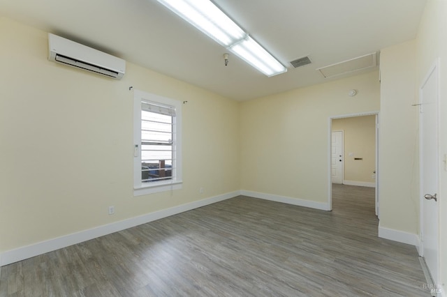 unfurnished room featuring wood-type flooring and a wall unit AC