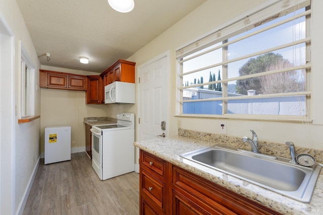 kitchen featuring sink, white appliances, light hardwood / wood-style flooring, light stone countertops, and a textured ceiling