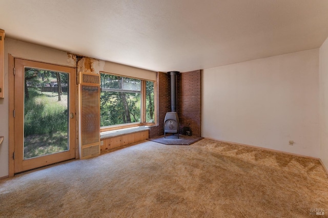 unfurnished living room with a wood stove and carpet flooring