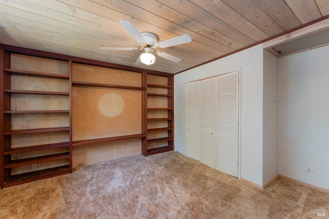 unfurnished bedroom featuring carpet flooring, wood ceiling, baseboards, ornamental molding, and a closet