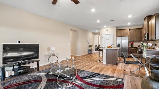 living room with ceiling fan and light hardwood / wood-style flooring