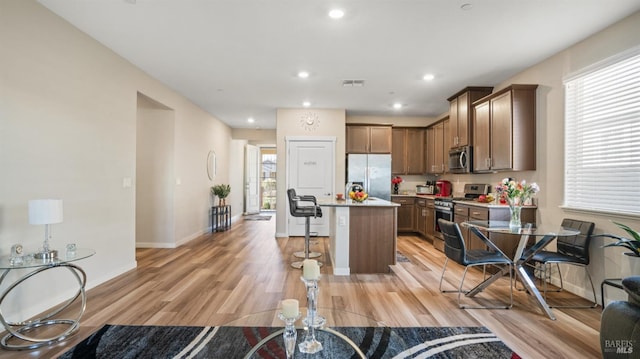 kitchen featuring a breakfast bar, a center island, light wood-type flooring, and stainless steel appliances