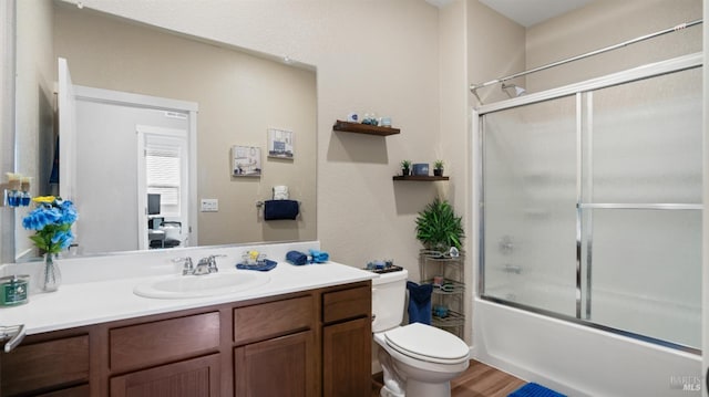 full bathroom featuring wood-type flooring, vanity, toilet, and bath / shower combo with glass door