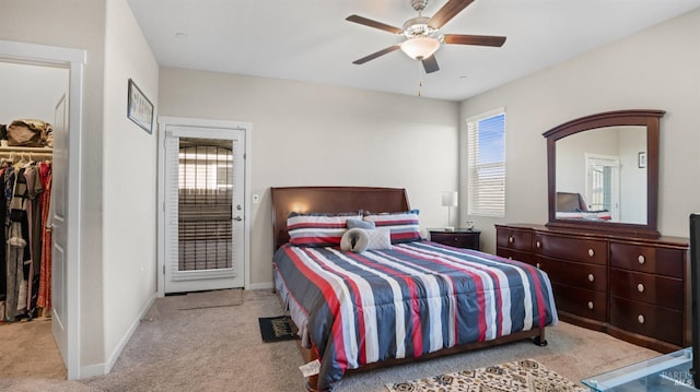 carpeted bedroom featuring multiple windows, a walk in closet, a closet, and ceiling fan