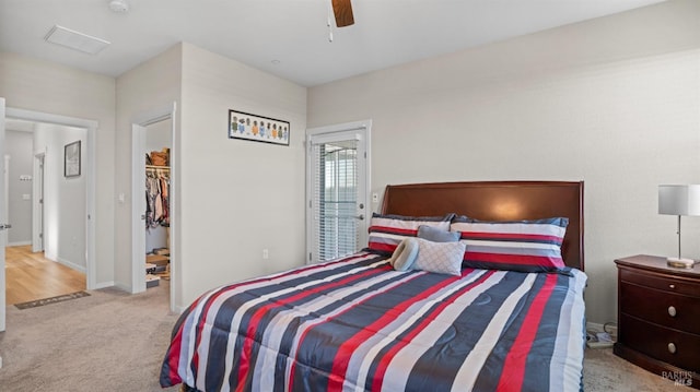 bedroom with a walk in closet, ceiling fan, a closet, and light carpet