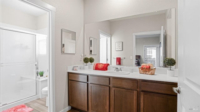 bathroom featuring vanity, wood-type flooring, an enclosed shower, and toilet