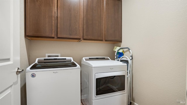 clothes washing area with cabinets and washing machine and clothes dryer