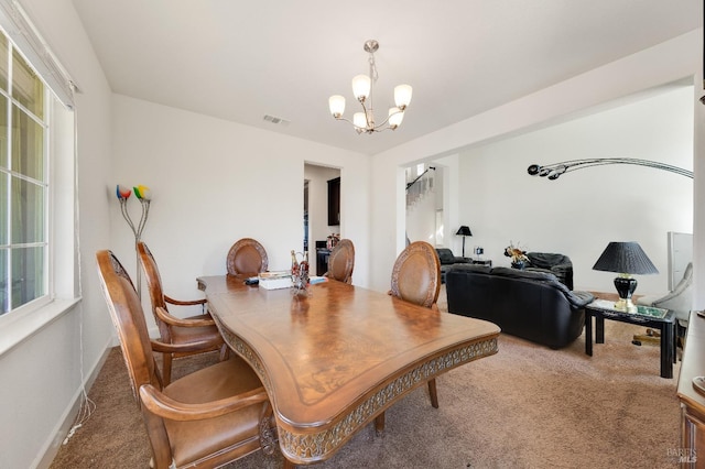 carpeted dining room featuring a healthy amount of sunlight and a notable chandelier