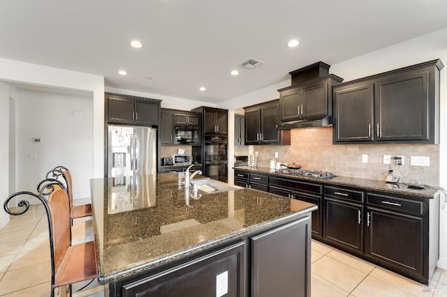 kitchen featuring black appliances, sink, light tile patterned floors, and an island with sink