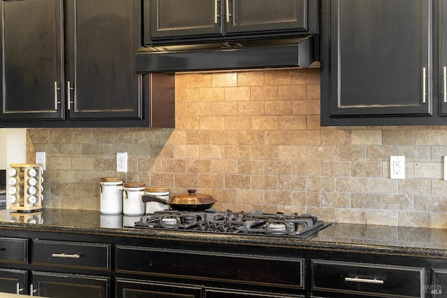 kitchen featuring ventilation hood, decorative backsplash, gas stovetop, and dark stone counters