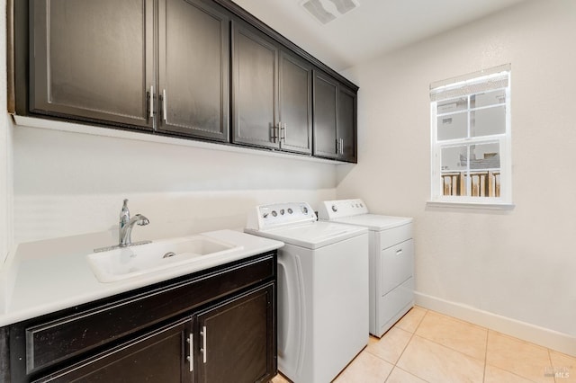 clothes washing area with washer and clothes dryer, light tile patterned flooring, cabinets, and sink