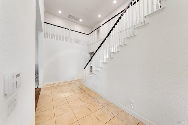 staircase featuring a high ceiling and tile patterned floors