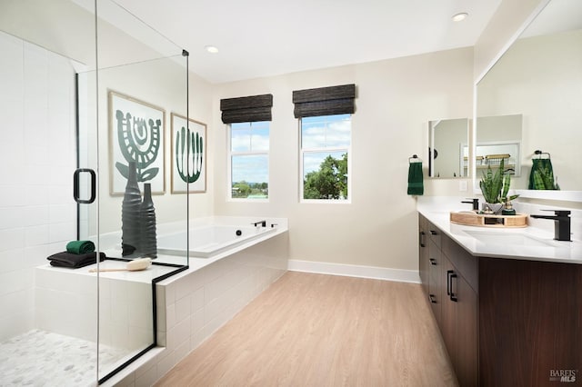 bathroom with hardwood / wood-style flooring, vanity, and plus walk in shower