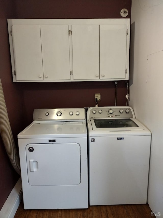 clothes washing area with dark hardwood / wood-style floors, washing machine and dryer, and cabinets