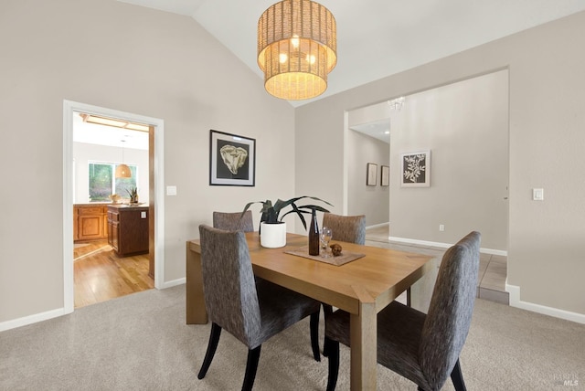 dining area with light carpet, an inviting chandelier, and vaulted ceiling