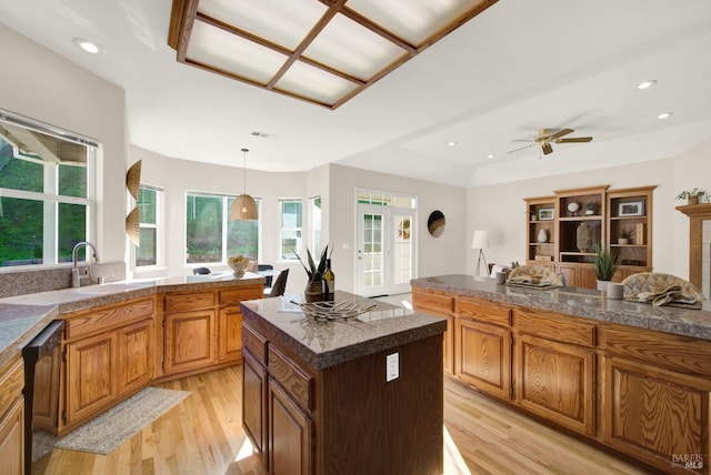 kitchen featuring a center island, hanging light fixtures, ceiling fan, light wood-type flooring, and black dishwasher