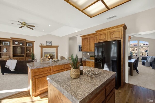 kitchen with backsplash, black appliances, vaulted ceiling, and hardwood / wood-style flooring