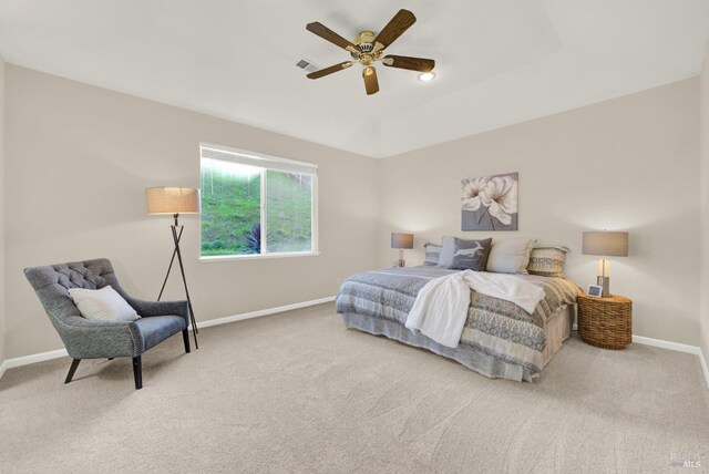 carpeted bedroom with a tray ceiling and ceiling fan