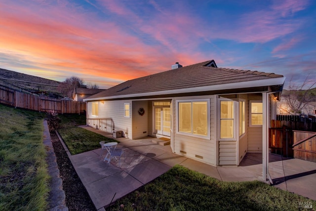 back house at dusk featuring a yard and a patio