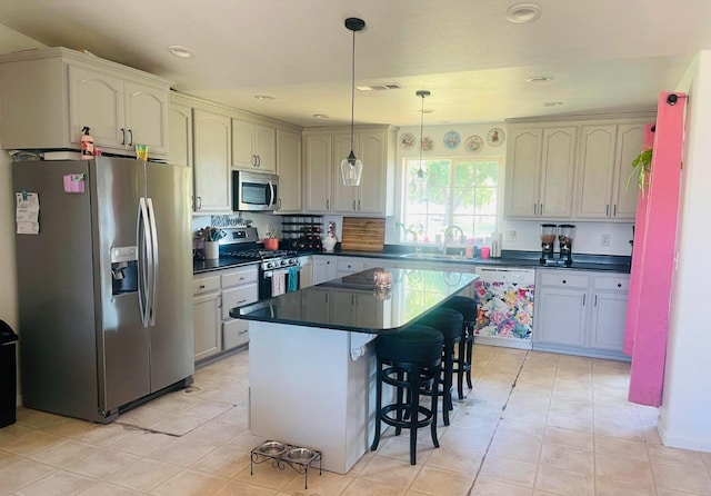 kitchen featuring pendant lighting, a breakfast bar, sink, a kitchen island, and stainless steel appliances