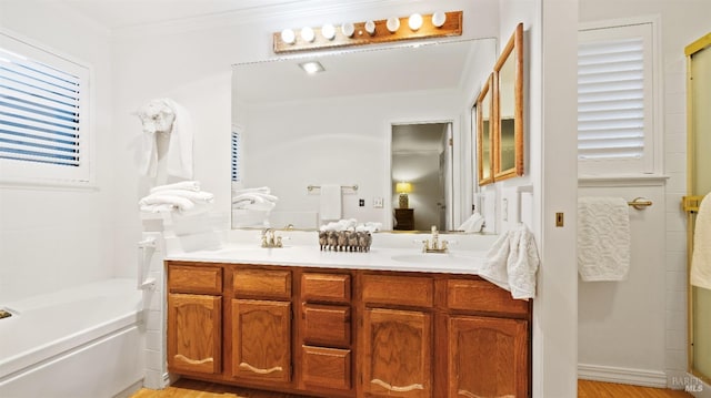 bathroom featuring hardwood / wood-style floors, vanity, ornamental molding, and a tub to relax in