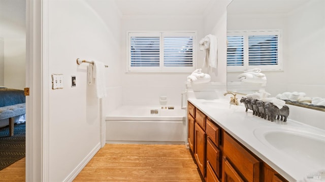 bathroom with a bathing tub, vanity, ornamental molding, and hardwood / wood-style floors