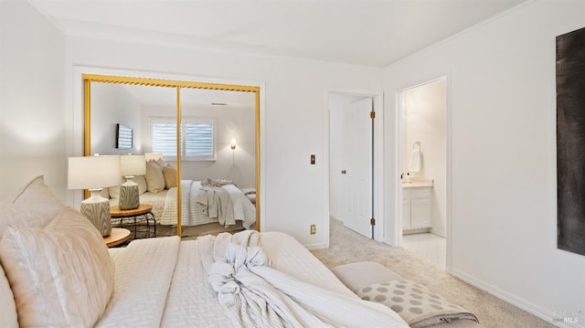 bedroom with connected bathroom, light carpet, and a closet