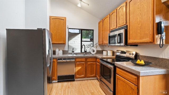 kitchen featuring light wood-type flooring, stainless steel appliances, lofted ceiling, and sink