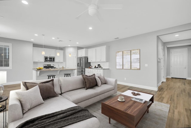 living room with ceiling fan and light hardwood / wood-style flooring