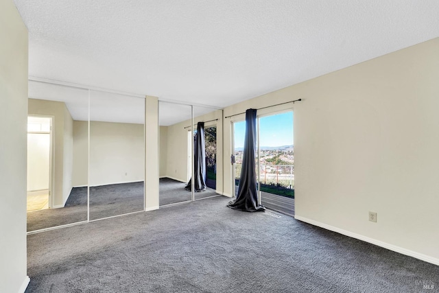 unfurnished room with dark carpet and a textured ceiling