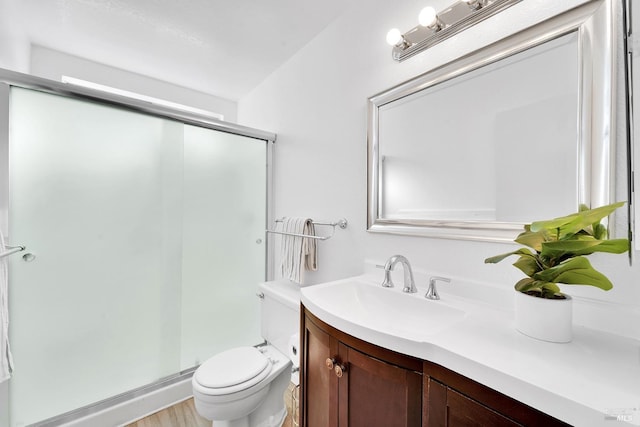 bathroom featuring a shower with door, vanity, and toilet