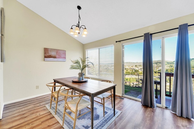 dining room featuring hardwood / wood-style floors, a healthy amount of sunlight, and an inviting chandelier