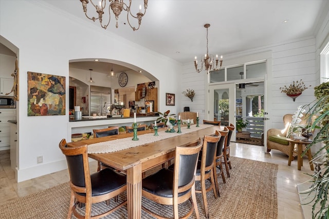 dining area featuring baseboards, arched walkways, an inviting chandelier, crown molding, and wood walls